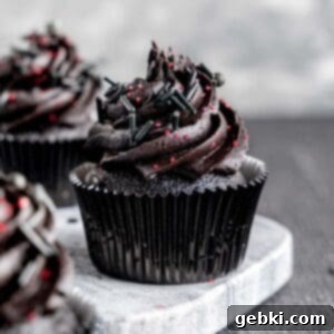 A black velvet cupcake with black cocoa frosting and red and black sprinkles.