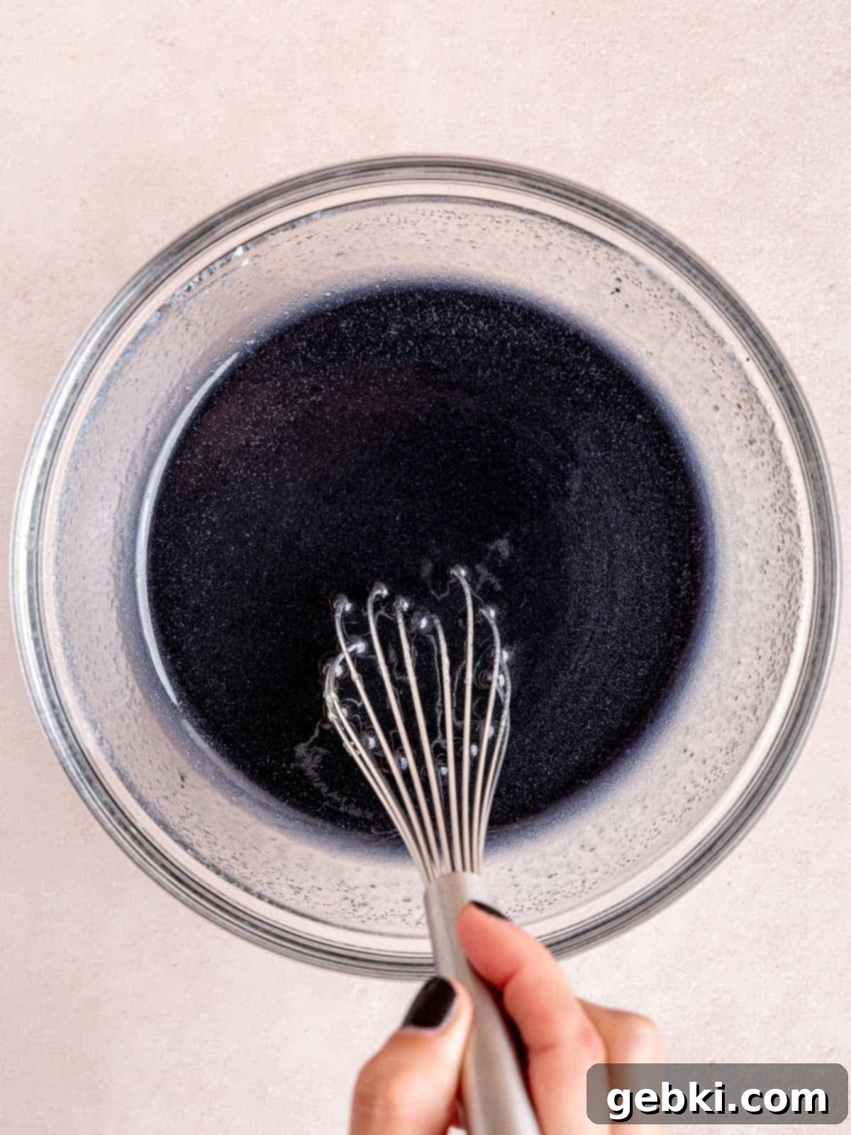 Whisking sugar, vegetable oil, egg, kefir, vinegar, and food coloring together in a bowl.