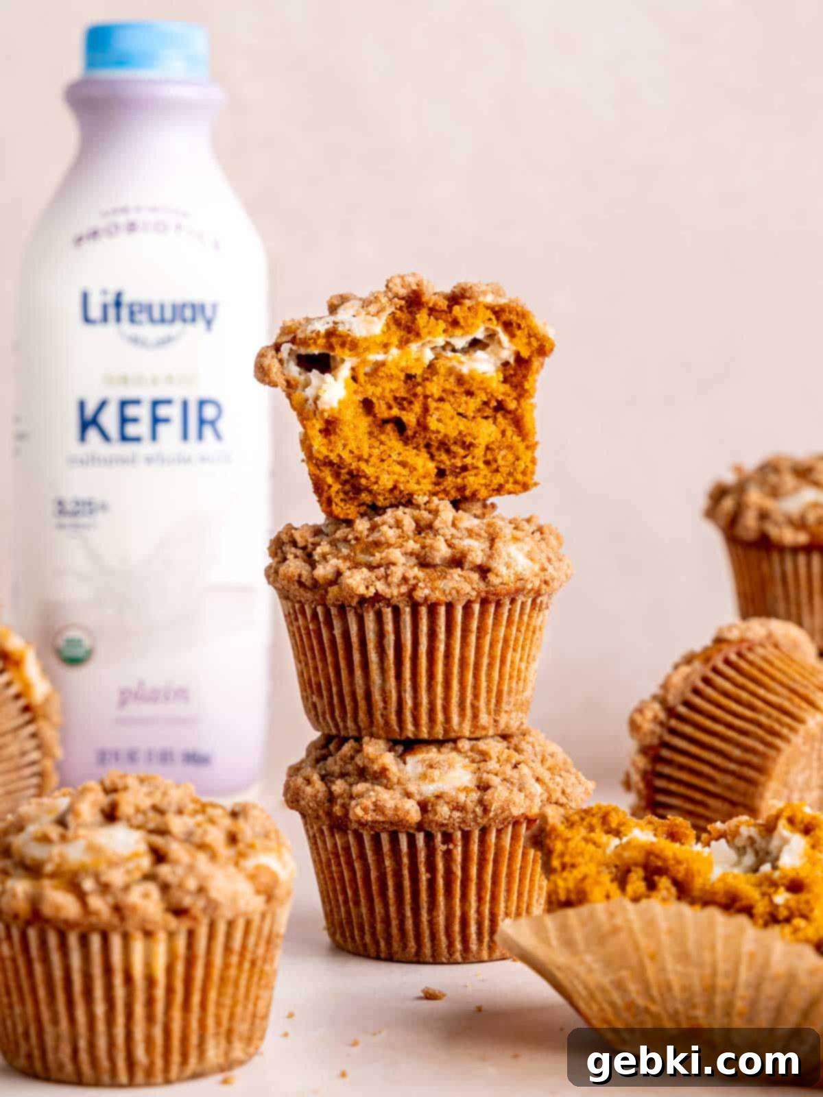 A beautiful stack of freshly baked pumpkin cream cheese muffins, with a bottle of Lifeway Kefir in the background, highlighting the key ingredient.