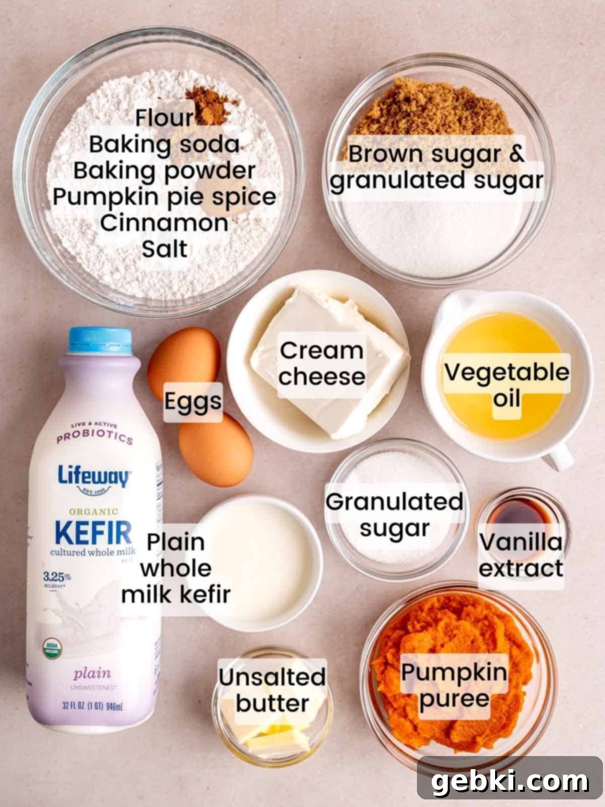 A curated selection of fresh ingredients, including pumpkin puree, cream cheese, kefir, spices, and flour, neatly arranged for making pumpkin muffins with cream cheese and streusel.