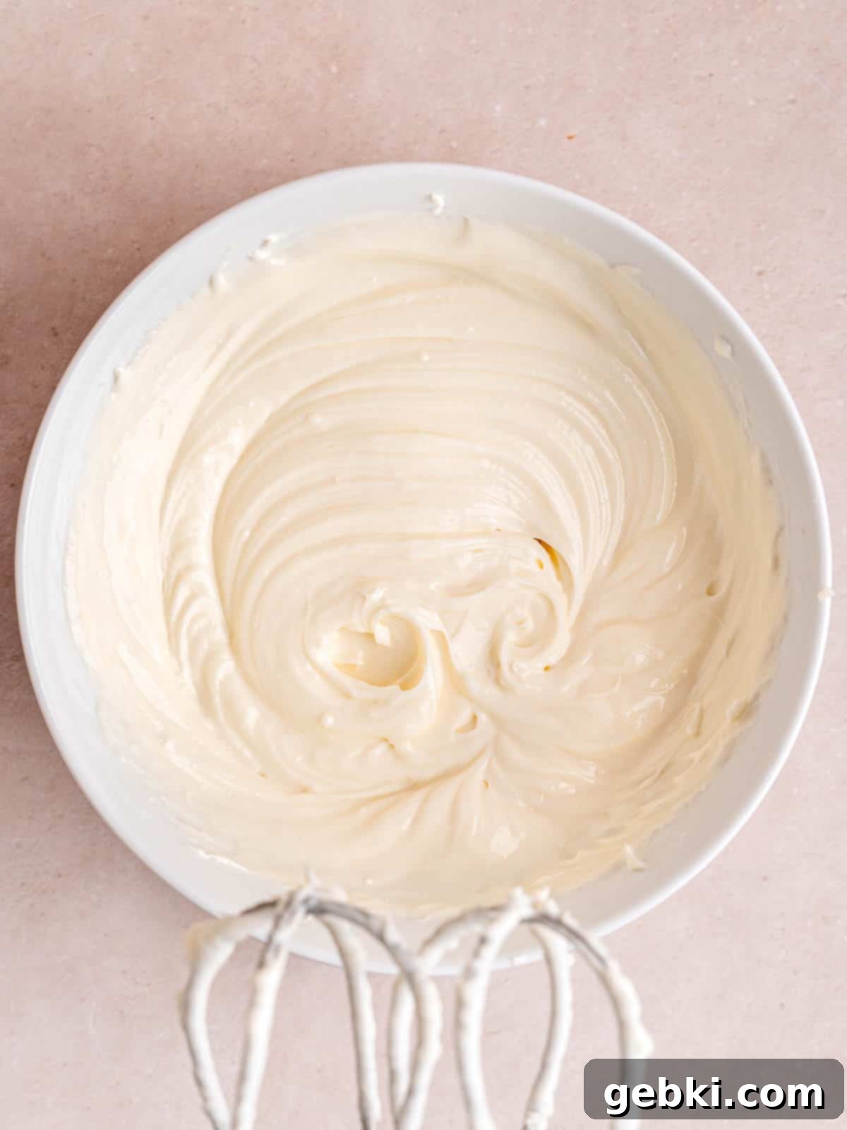 Cream cheese, granulated sugar, and kefir perfectly mixed together in a white bowl, ready for the muffin filling.