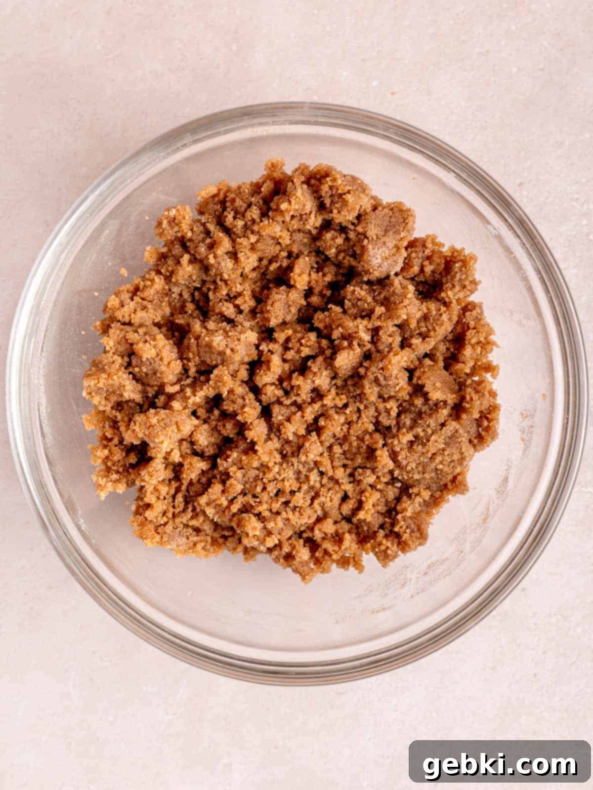 A bowl filled with a golden, crumbly cinnamon streusel topping, showcasing its sweet and spiced texture.