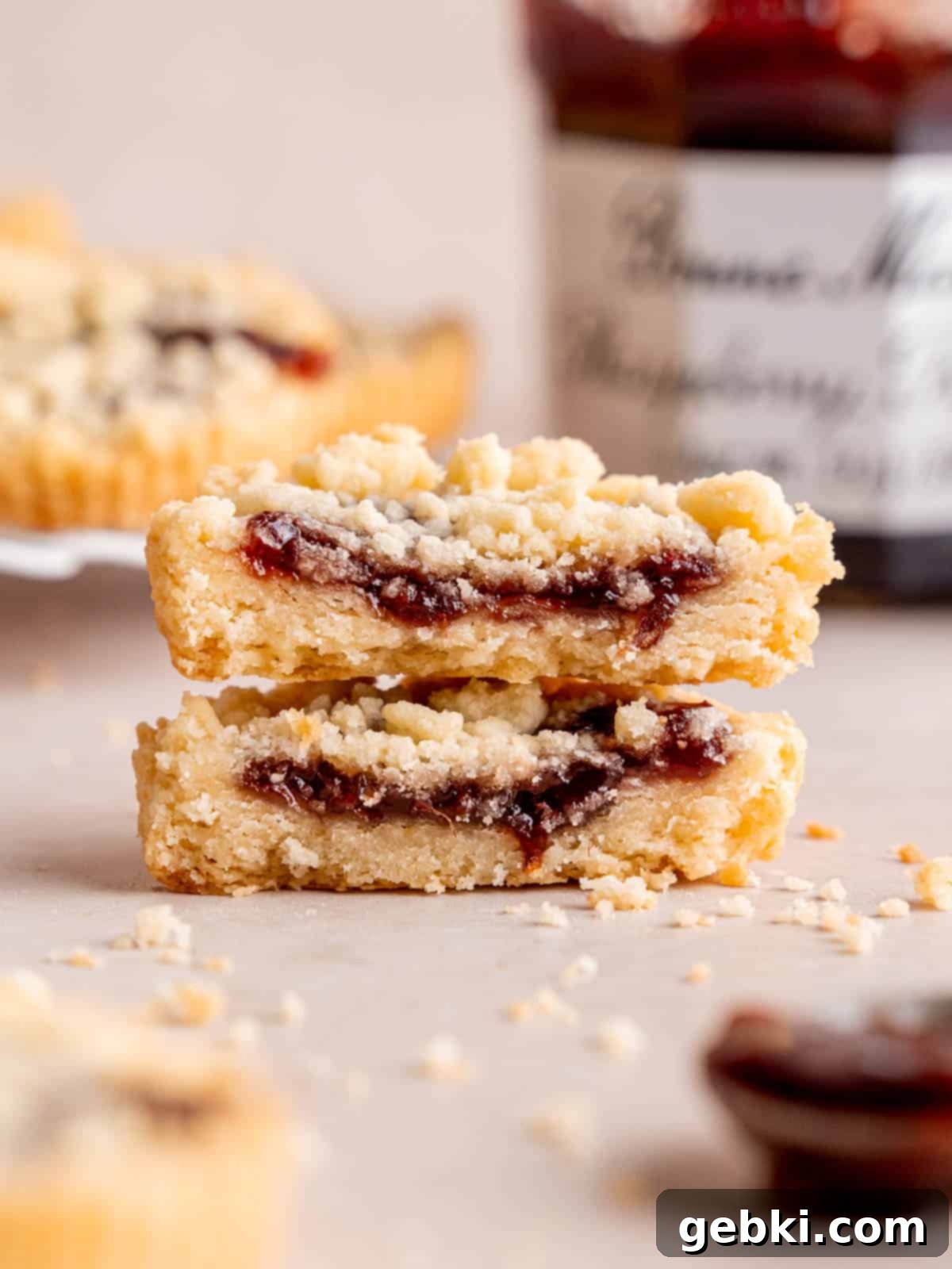 Simply Superior Easy Raspberry Crumble Cookies 2 Two halves of a raspberry crumble cookie stacked on top of each other, showcasing the jam filling and crumbly topping.