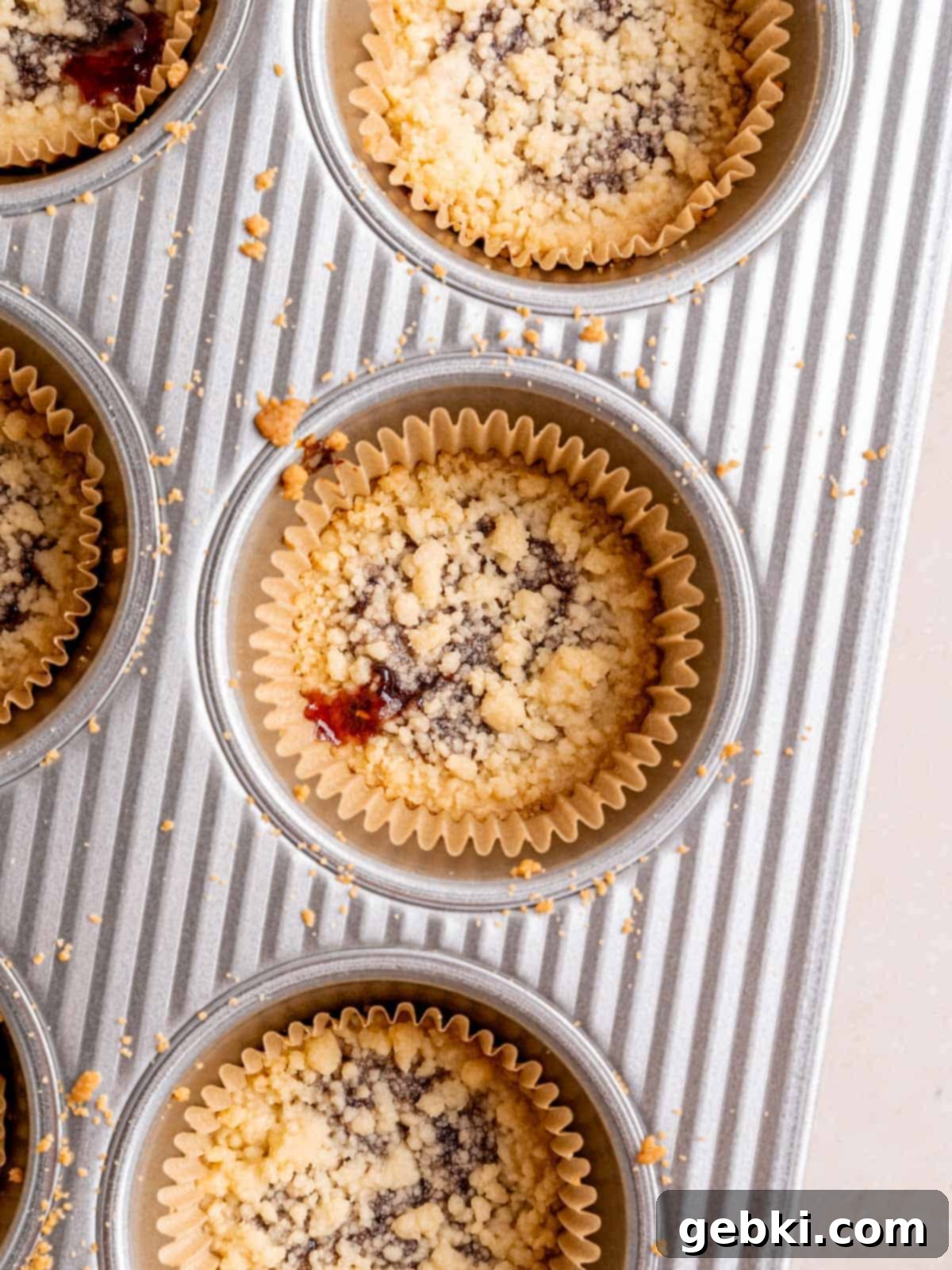 Simply Superior Easy Raspberry Crumble Cookies 9 Baked shortbread cookies with raspberry filling in a muffin pan, showing golden-brown edges.