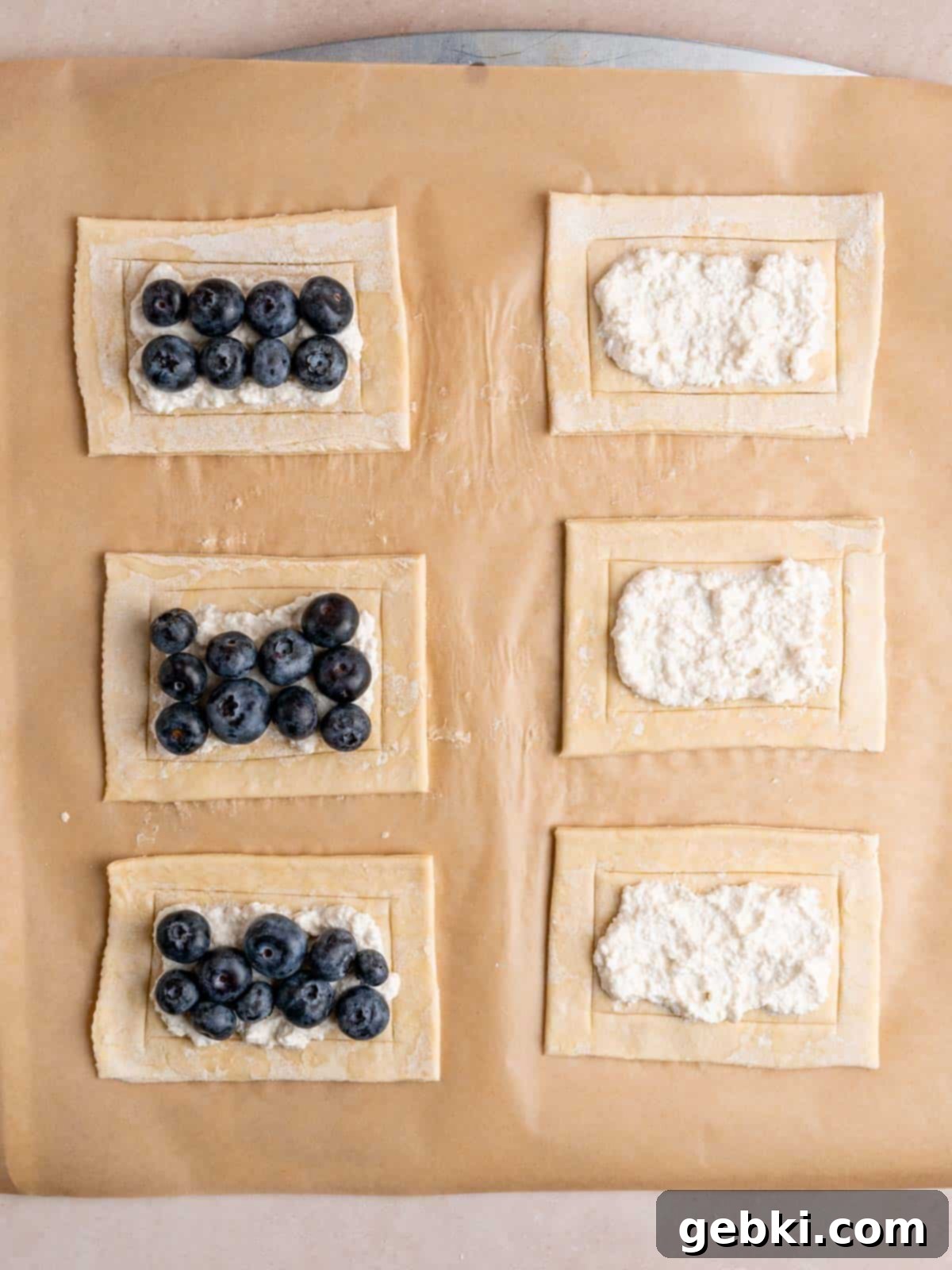 Simple Blueberry Cream Cheese Puffs 6 A puff pastry sheet cut into 6 rectangles with cheese filling spread on the inner rectangles and fresh blueberries on top.