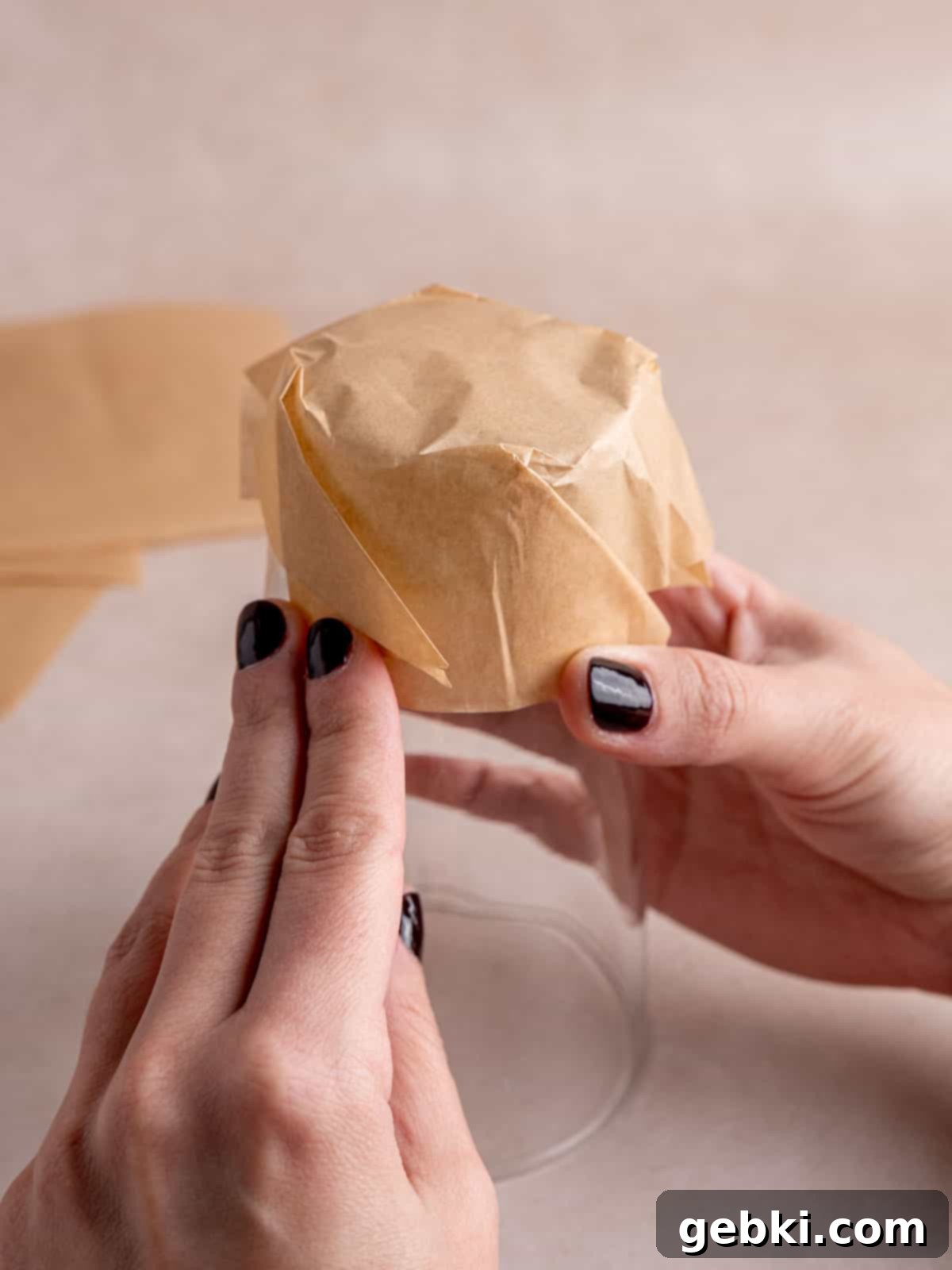 The Ultimate Guide To Homemade Muffin Liners 9 A parchment paper square folded over the bottom of a pint glass.