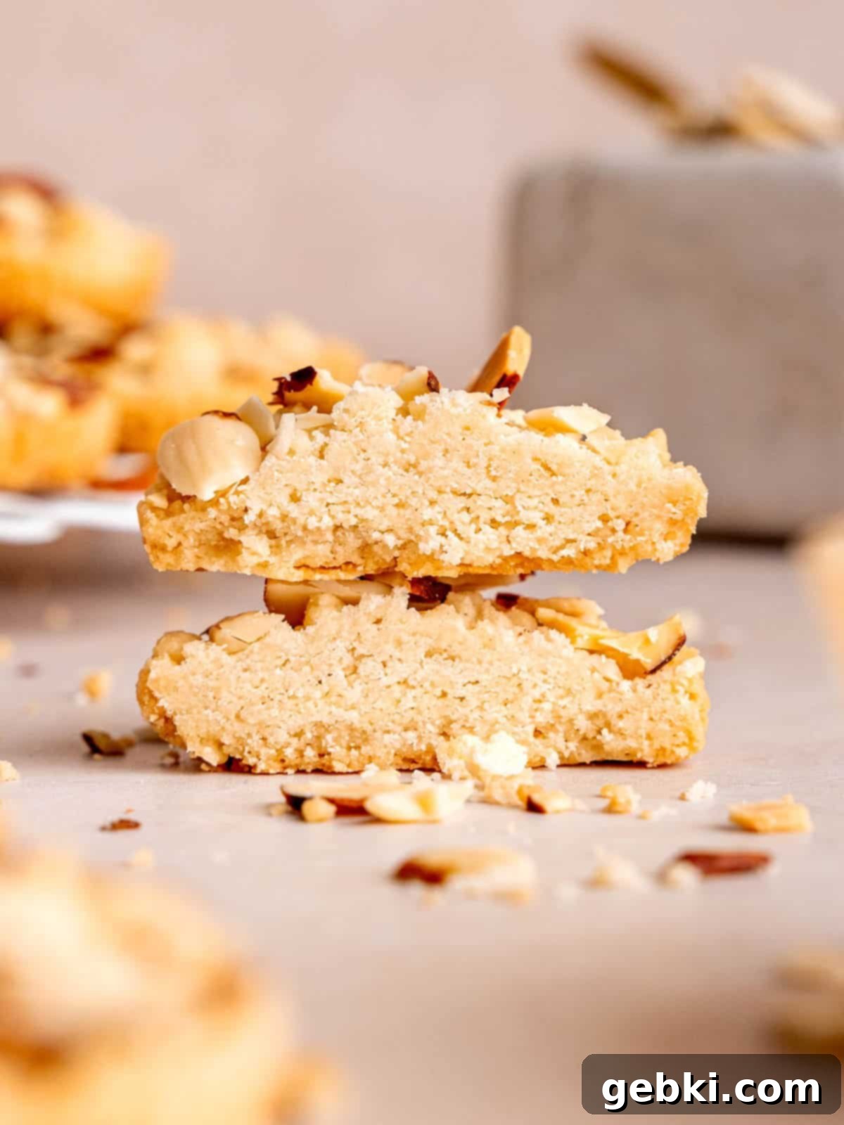 A beautiful stack of almond croissant shortbread cookies, with one cookie cut in half to reveal its rich, moist almond filling and crumbly layers.