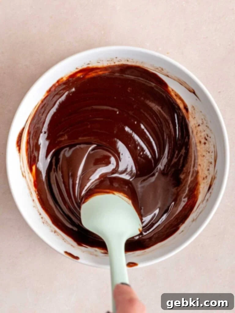 Stirring chocolate ganache with a rubber spatula.