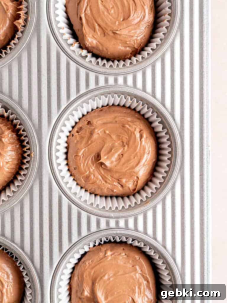 A cupcake pan filled with chocolate cheesecake on top of Oreo crumb crusts.