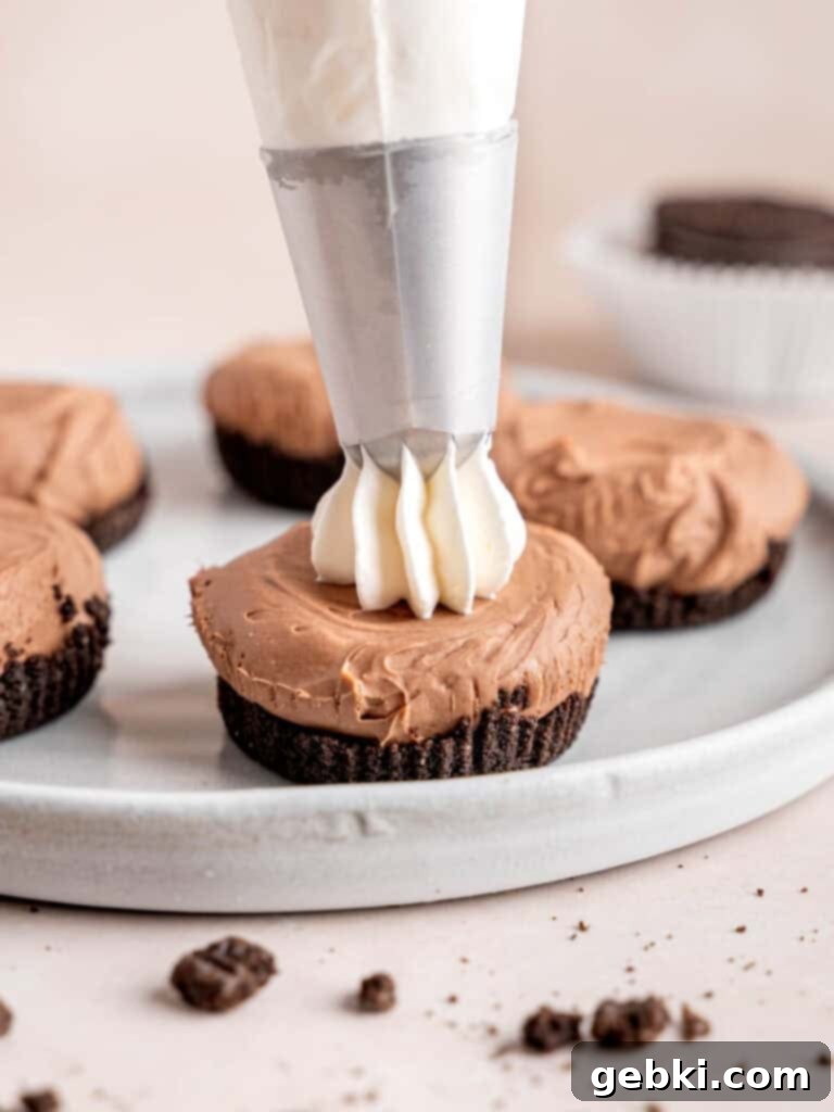 Piping whipped cream on top of a mini chocolate cheesecake.