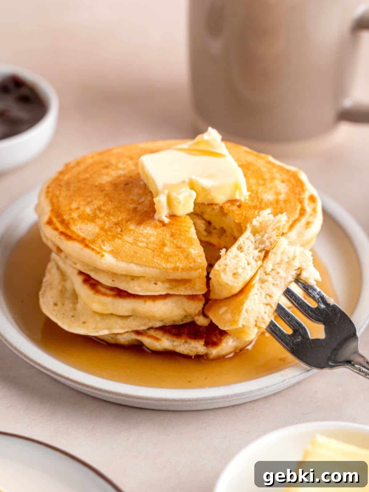 A stack of fluffy kefir pancakes topped with butter and maple syrup.