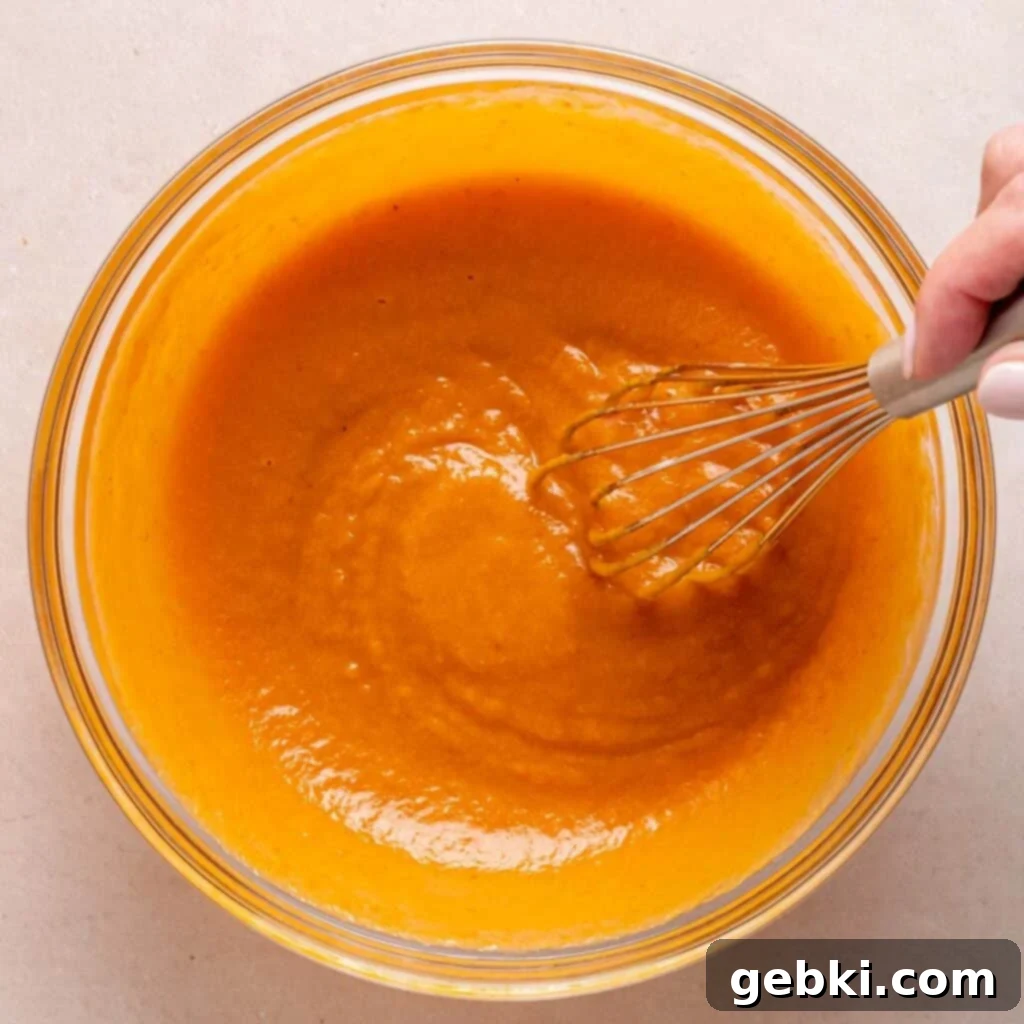 Whisking egg, vanilla extract, vegetable oil, kefir, sugars, and pumpkin in a bowl to combine wet ingredients.