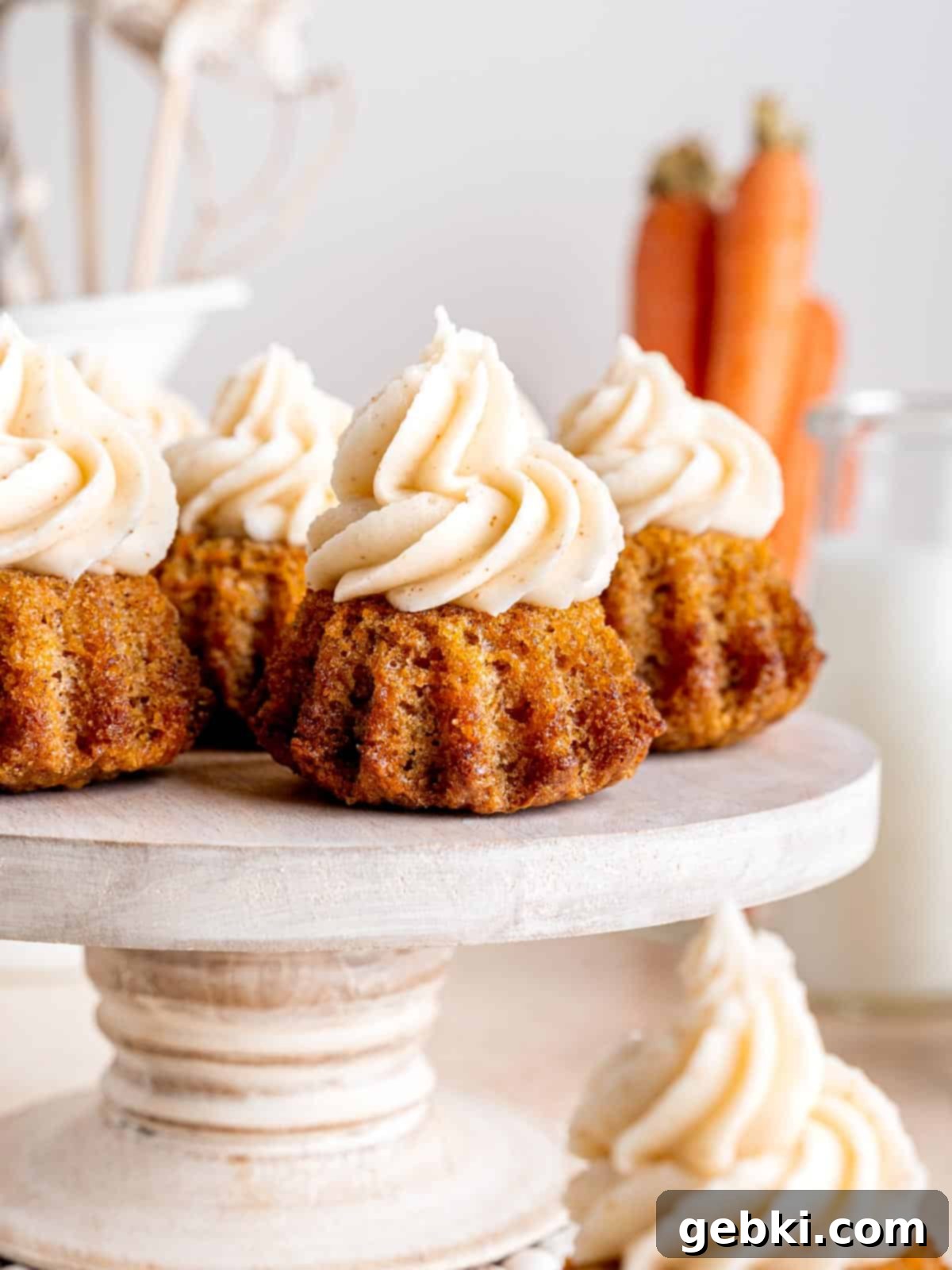 Perfect Carrot Cake Cupcakes 2 The best carrot cake cupcakes on a cake pan with swirls of brown butter cream cheese frosting on top.
