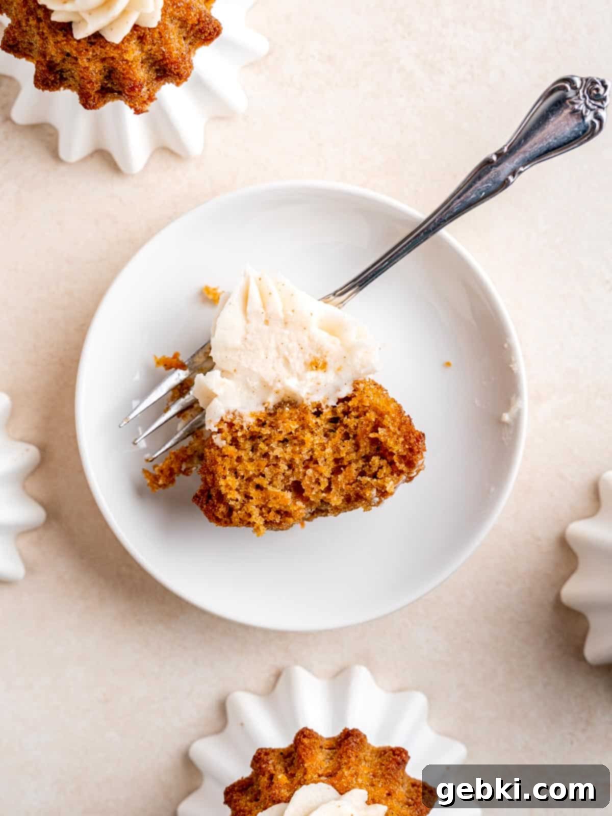 Perfect Carrot Cake Cupcakes 6 A carrot cake cupcake on a plate with a bite taken out of it showing the fluffy texture.