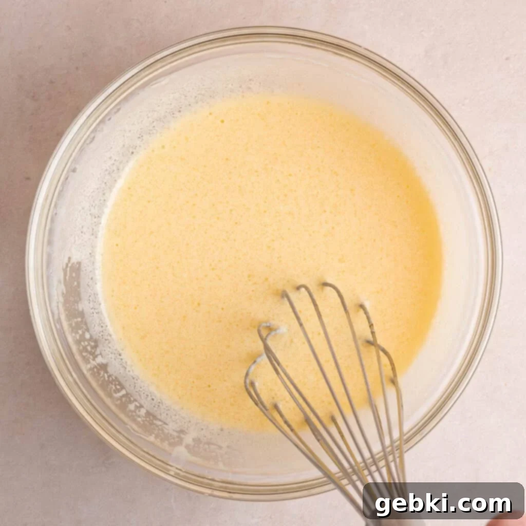 Whisking an egg, vegetable oil, vanilla extract, and kefir in a bowl.