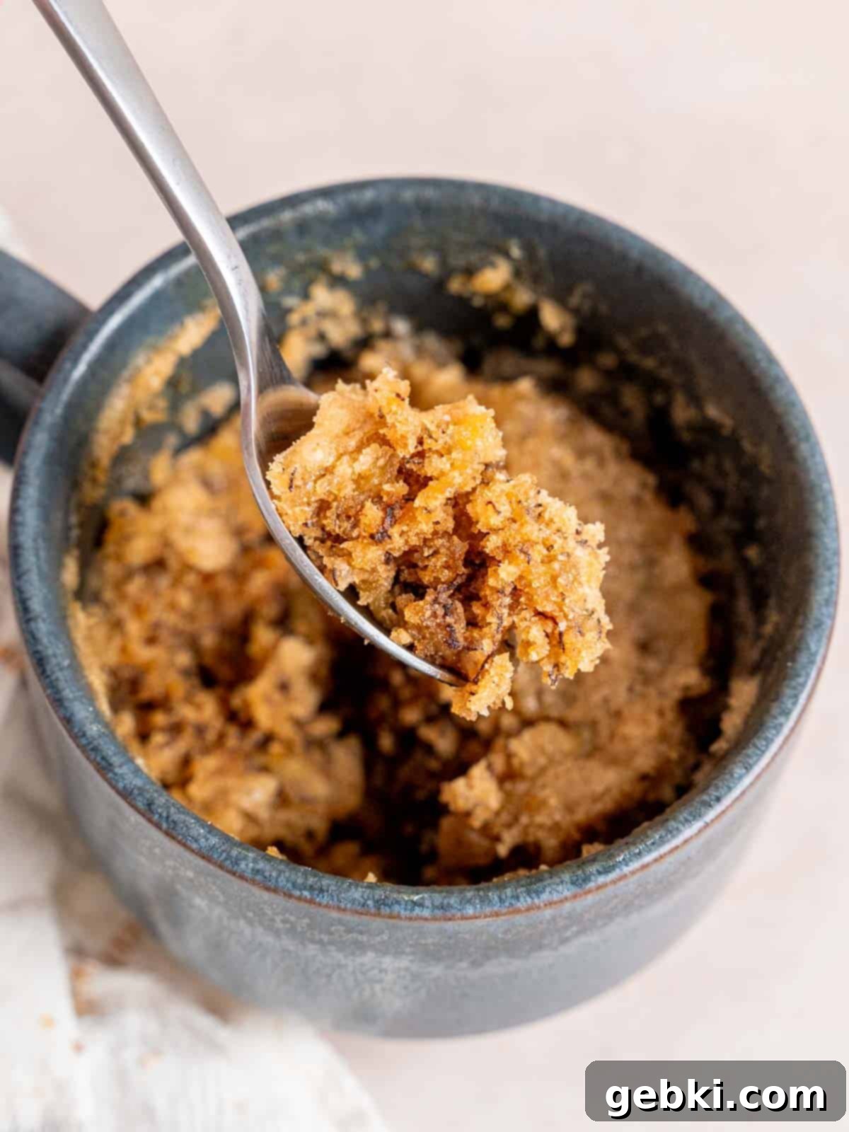 Speedy Eggless Banana Bread Mug Cake 2 A bite of warm, soft banana bread mug cake on a spoon, ready to be enjoyed.