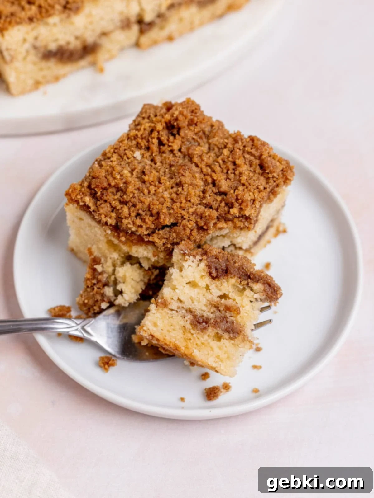 Tangy Sourdough Discard Coffee Cake 11 A fork cutting a bite out of a slice of sourdough coffee cake, revealing the fluffy texture and cinnamon streusel layers.