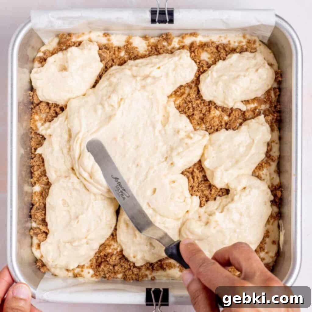 Tangy Sourdough Discard Coffee Cake 9 Spreading the second layer of cake batter over the streusel in a baking pan.