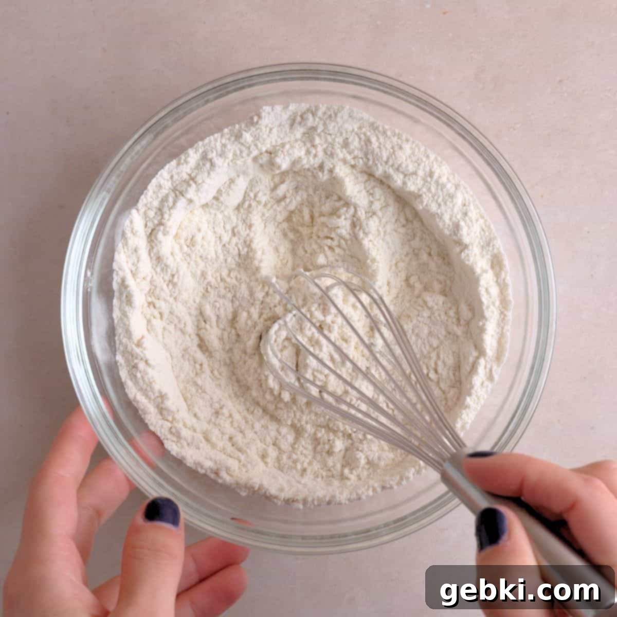 Flour, baking soda, and salt being whisked in a bowl.