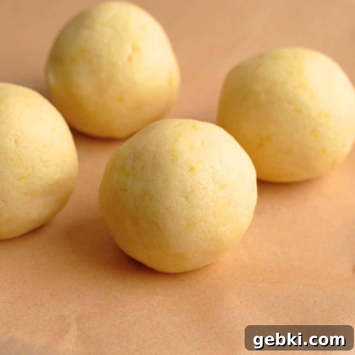 Lemon cookie dough balls on a sheet of parchment paper.