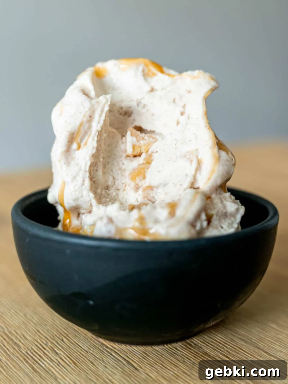 Ninja Creami Apple Pie Delight 2 A scoop of caramel apple pie cheesecake ice cream with a bite taken out of it, showcasing its creamy texture and apple chunks.