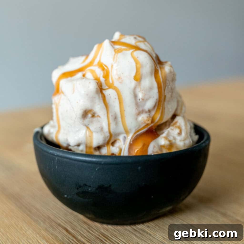 Ninja Creami Apple Pie Delight 8 Apple cheesecake ice cream in a bowl with caramel sauce drizzled on top, ready to be enjoyed.