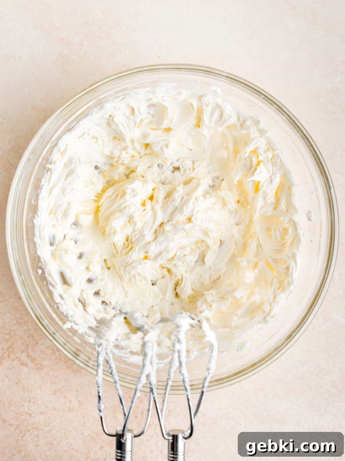 Cream cheese mixture in a bowl with a hand mixer.