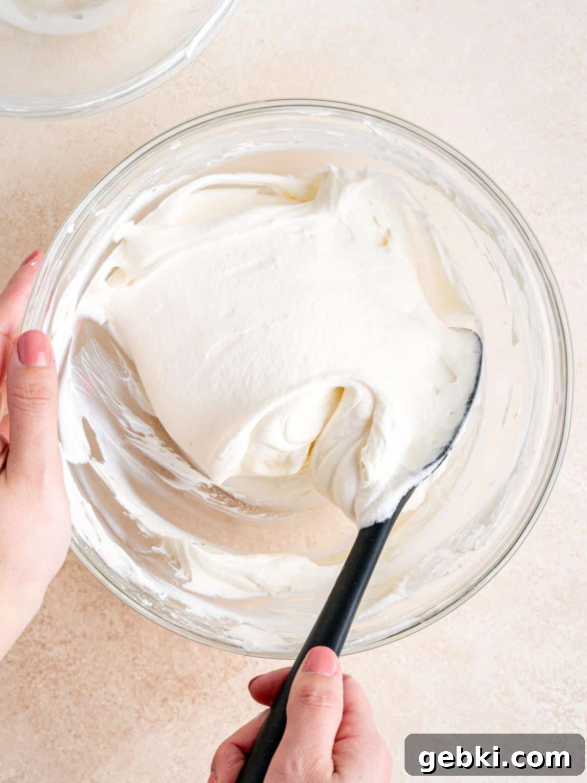 Folding whipped cream into cream cheese mixture with a rubber spatula.
