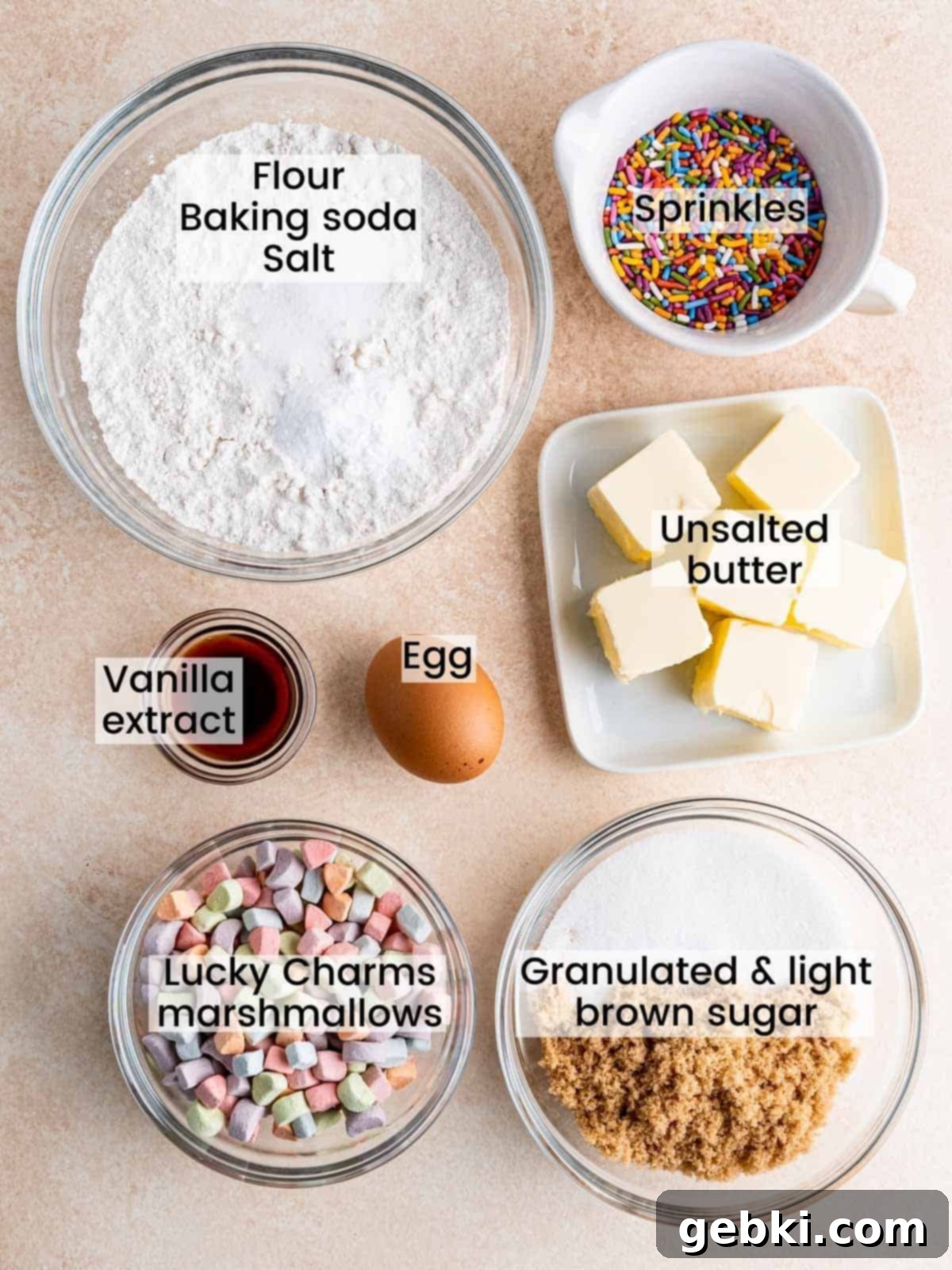 A flat lay photograph showcasing all the dry and wet ingredients neatly arranged on a white surface, ready to be mixed for the Lucky Charms cookie recipe.