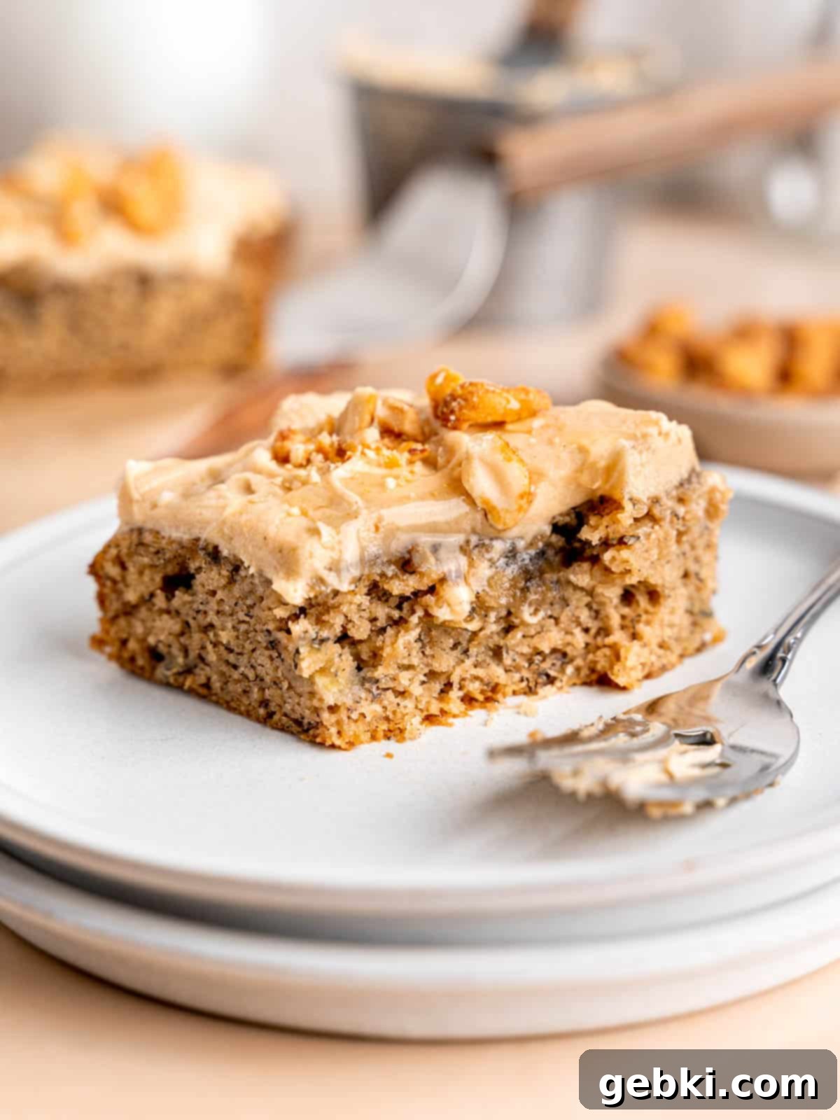 The Easiest Frosted Banana Cake Ever 1 A slice of banana snack cake on a plate with a fork.