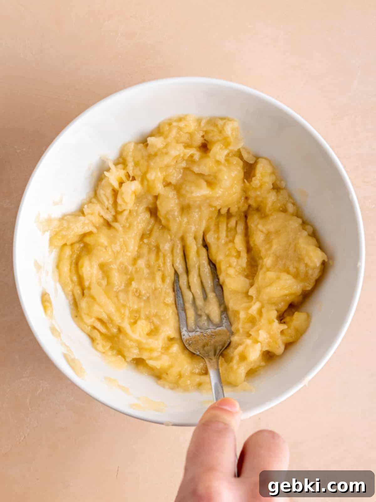 The Easiest Frosted Banana Cake Ever 3 Mashing overripe bananas in a bowl with a fork.