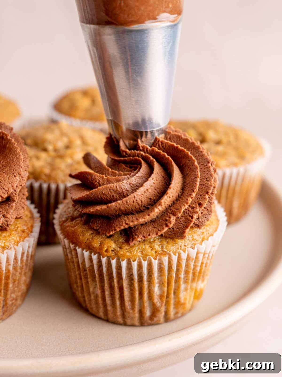 Banoffee Bliss Cupcakes 11 Piping whipped chocolate ganache in a swirl on top of a dulce de leche filled banana cupcake.