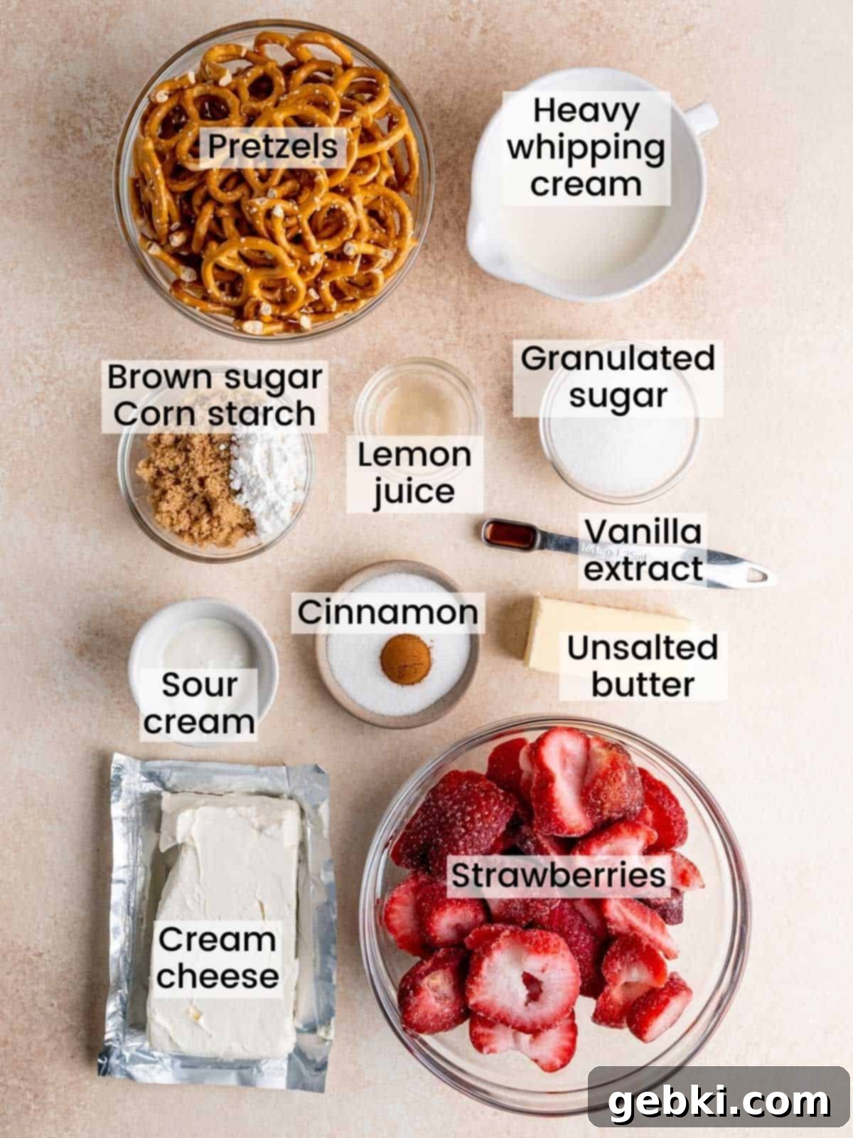 A flat lay of all the fresh and pantry ingredients needed to make a strawberry cream cheese pie with a pretzel crust.