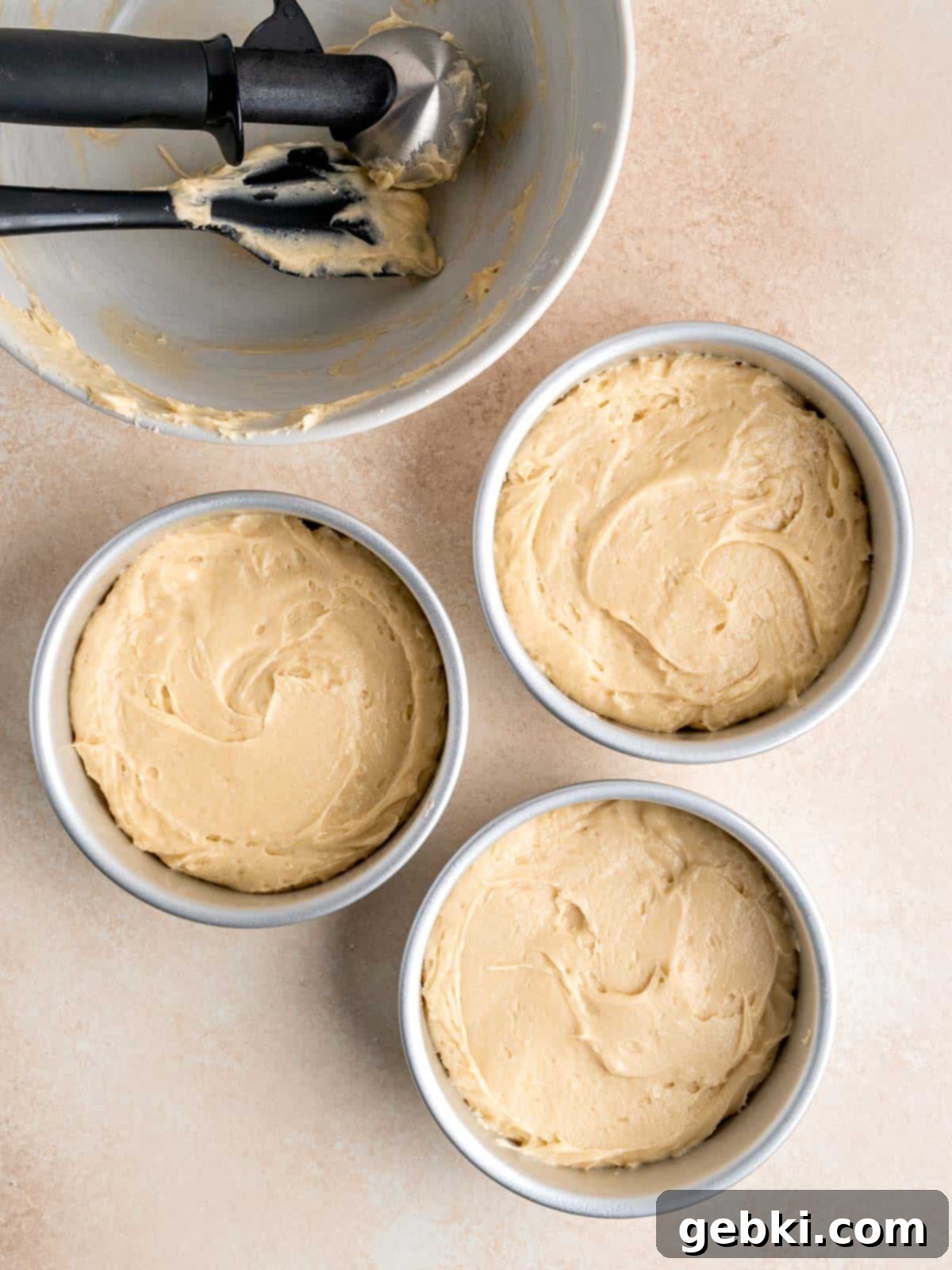 Effortless Honey Vanilla Delight 7 Three 6-inch round cake pans evenly filled with honey vanilla cake batter, ready for baking.