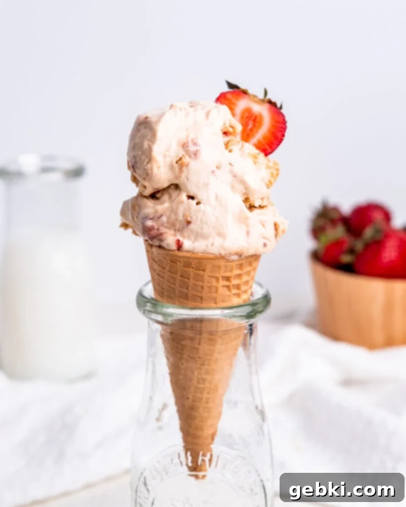Strawberry Swirl Cheesecake Delight 2 A scoop of strawberry cheesecake ice cream in a sugar cone with a strawberry slice on top