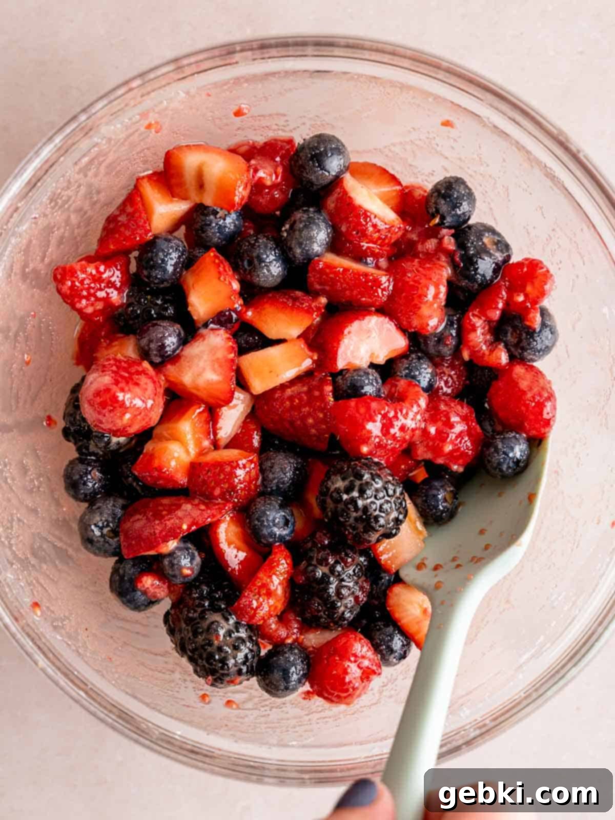 Mixing blueberries, strawberries, raspberries, blackberries, brown sugar, lemon juice, and corn starch in a bowl.