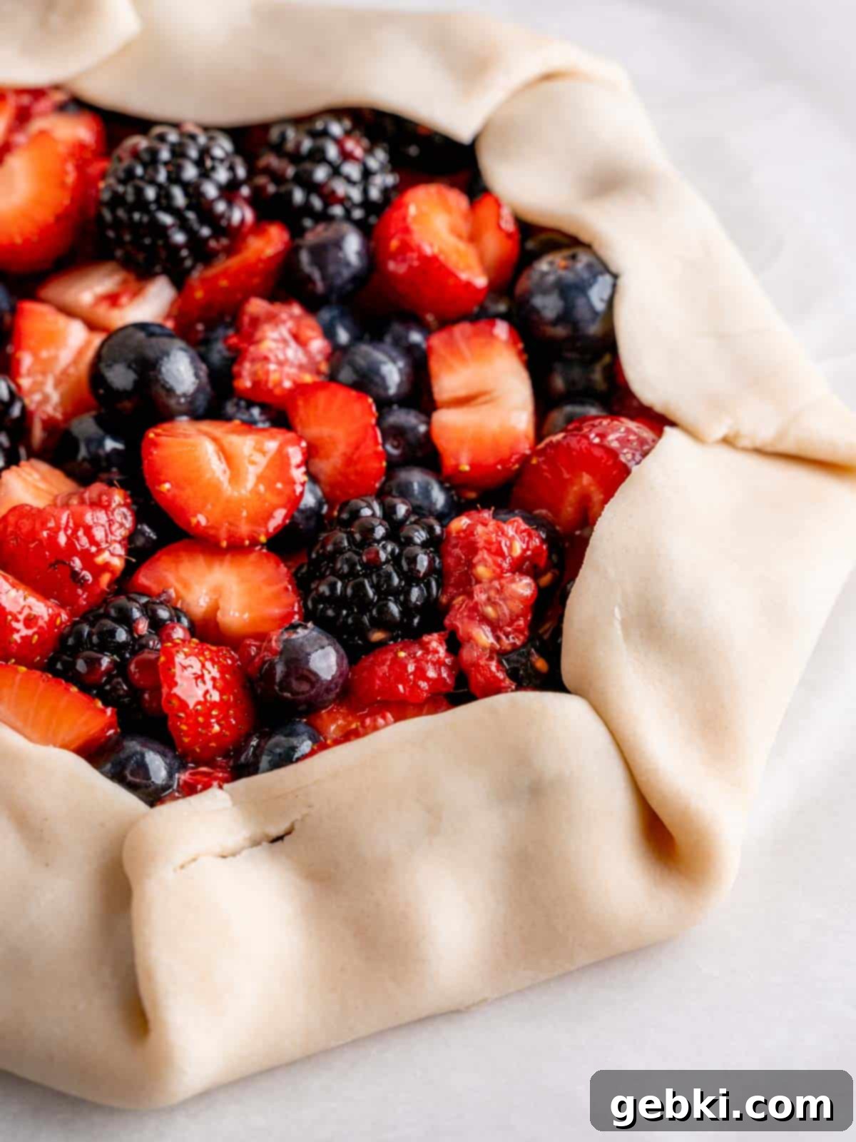 A pie crust with its edges folded over mixed berries, forming the galette shape.