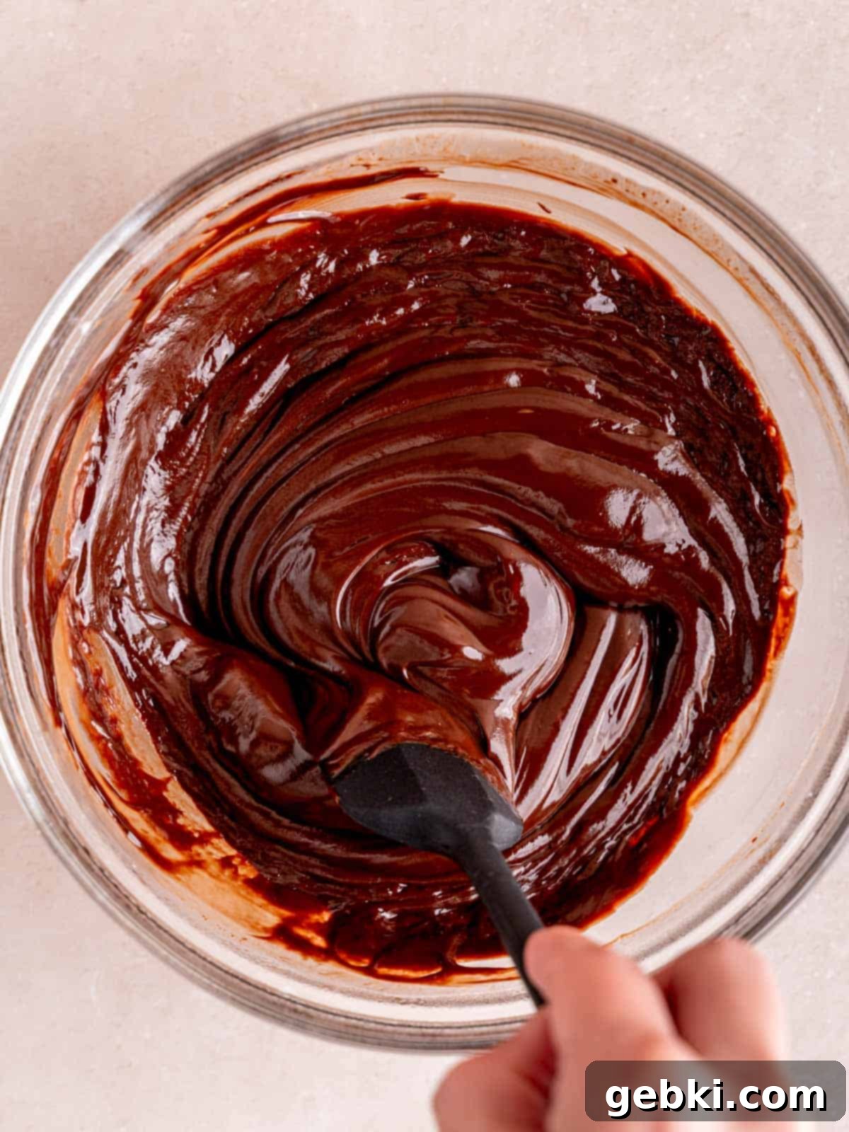No-Bake Chocolate Cherry Cheesecake 7 Stirring silky chocolate ganache in a bowl with a spatula.