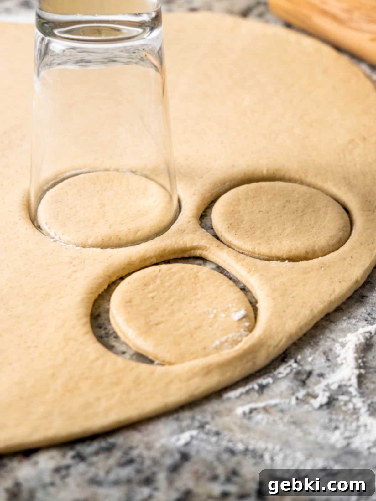 Gooey S'mores Stuffed Donuts 5 Hands using a pint glass to cut round donut shapes from a sheet of risen dough on a lightly floured surface.