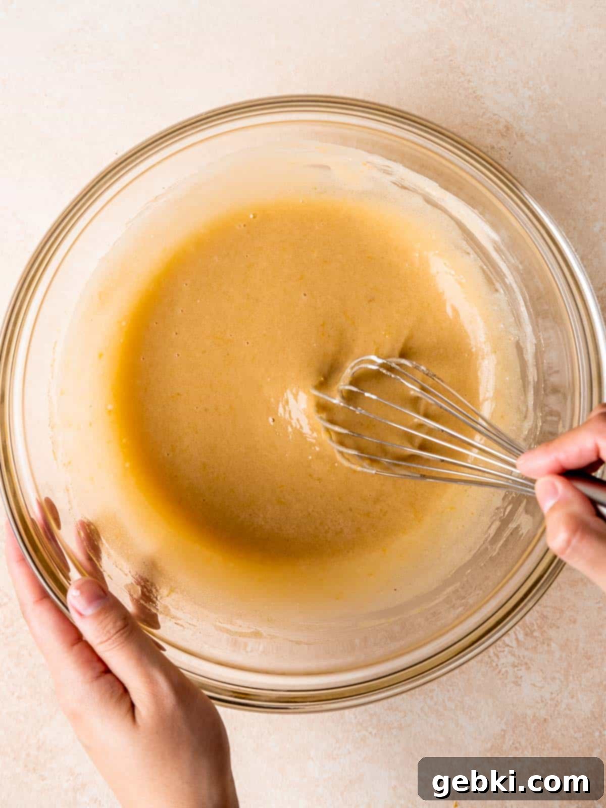 Whisking sugars, canola oil, lemon zest, vanilla extract and sour cream in a bowl.