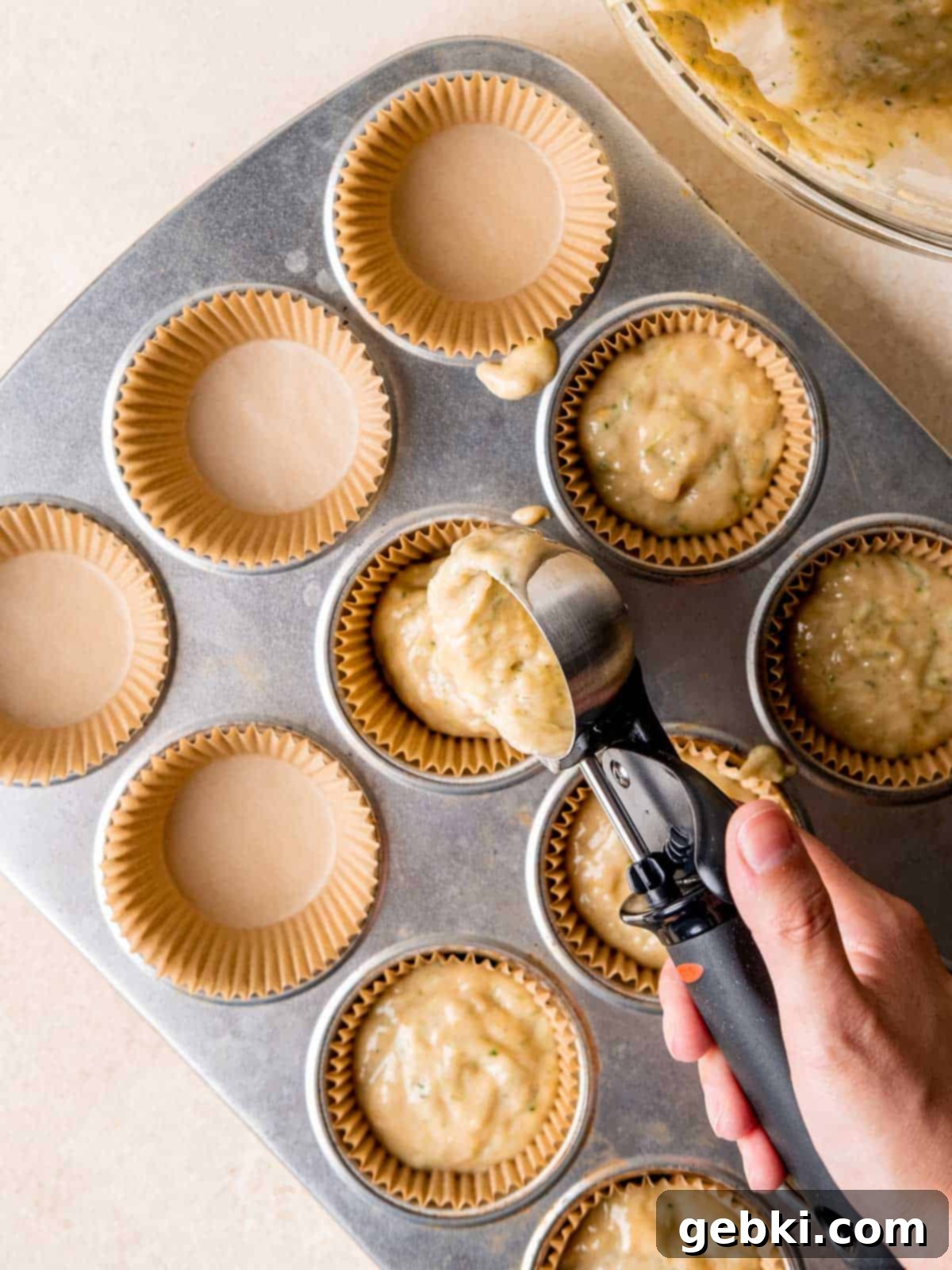 Scooping cupcake batter into cupcake liners.