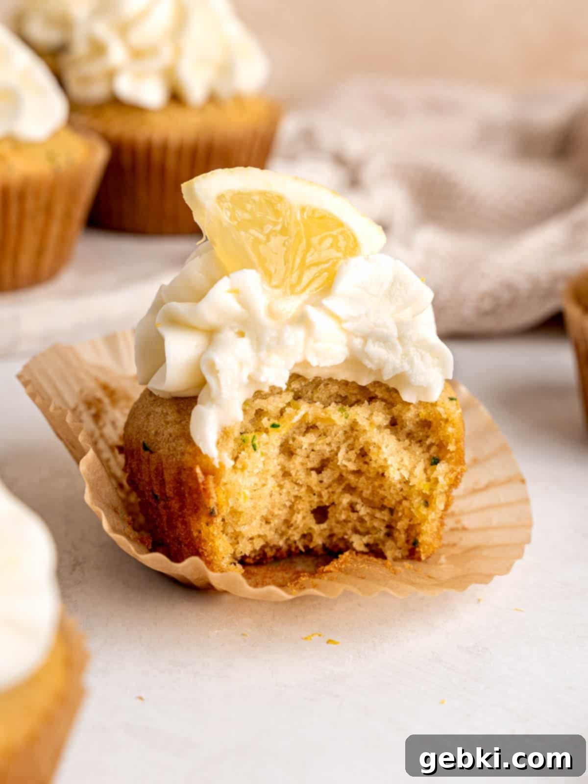 A lemon zucchini cupcake with a bite taken out of it.