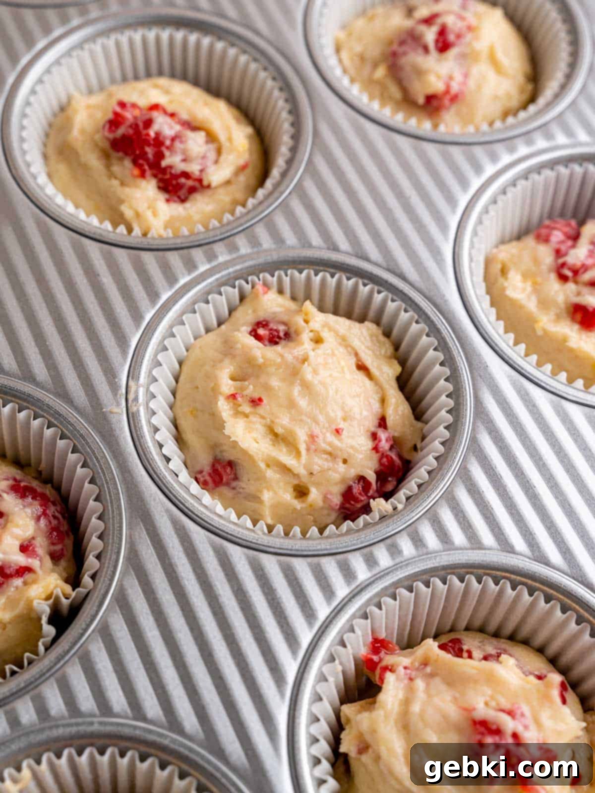 Irresistible Lemon Raspberry Muffins 8 Muffin liners filled with lemon raspberry muffin batter, ready for baking.
