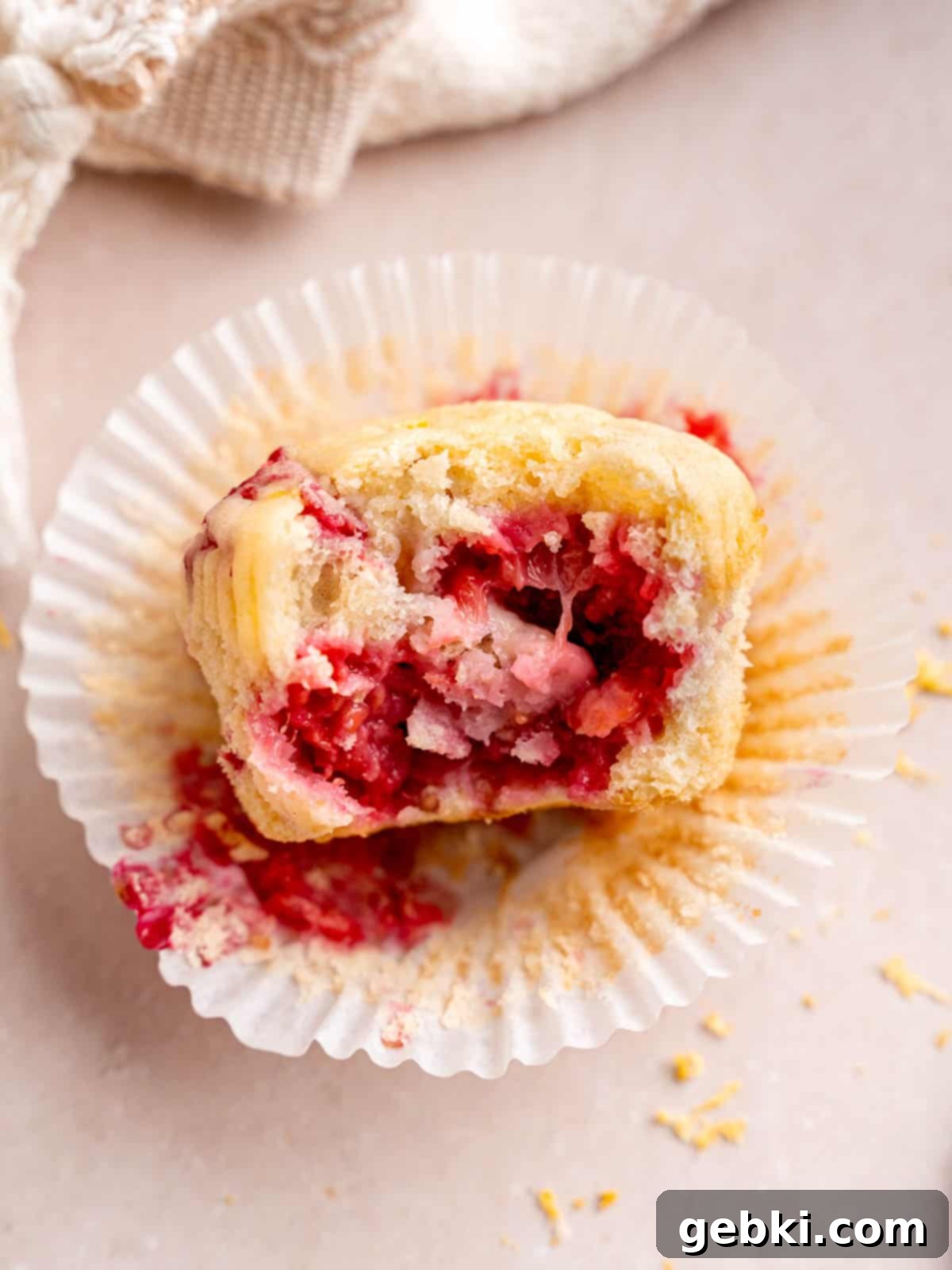 Irresistible Lemon Raspberry Muffins 9 A lemon muffin with raspberries that has a bite taken out of it, showing the moist interior.