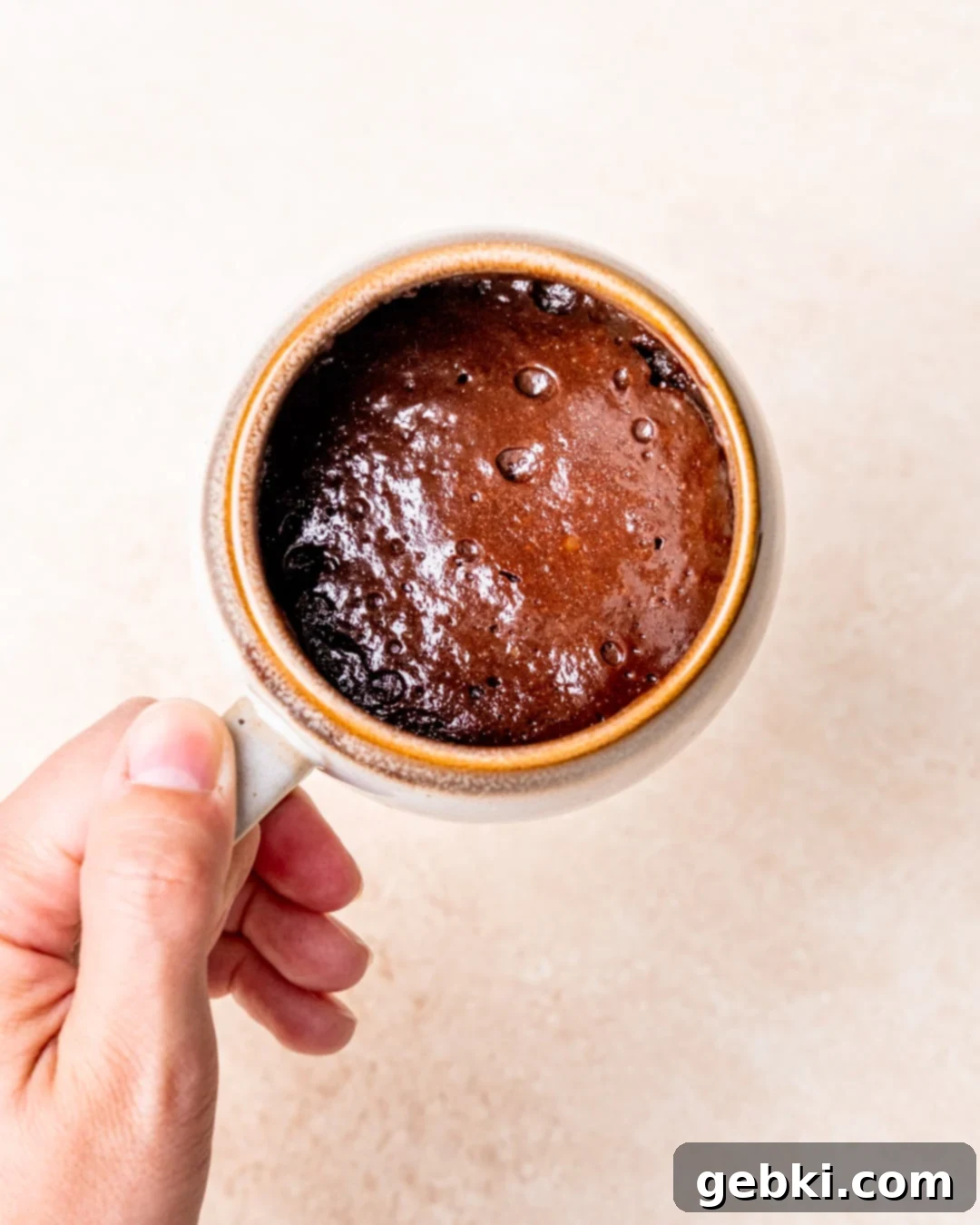 Decadent Fudgy Mug Brownie 2 A hand holding a mug filled with a fudgy brownie