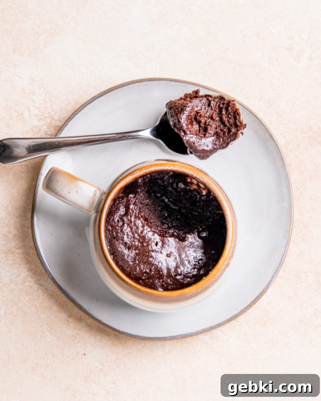 Decadent Fudgy Mug Brownie 8 A fudgy mug brownie on a plate with a spoonful of brownie next to it