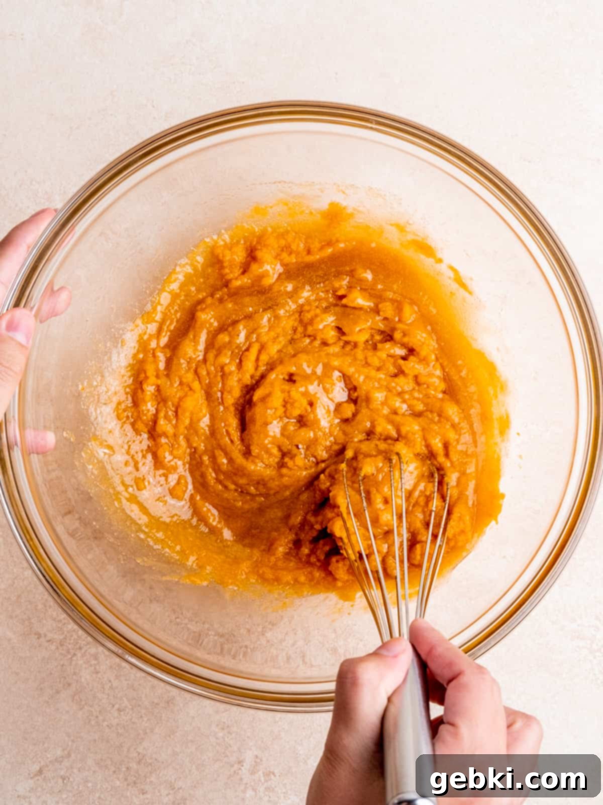 Whisking oil, sugars, egg, vanilla extract and pumpkin puree in a bowl for the pumpkin batter.