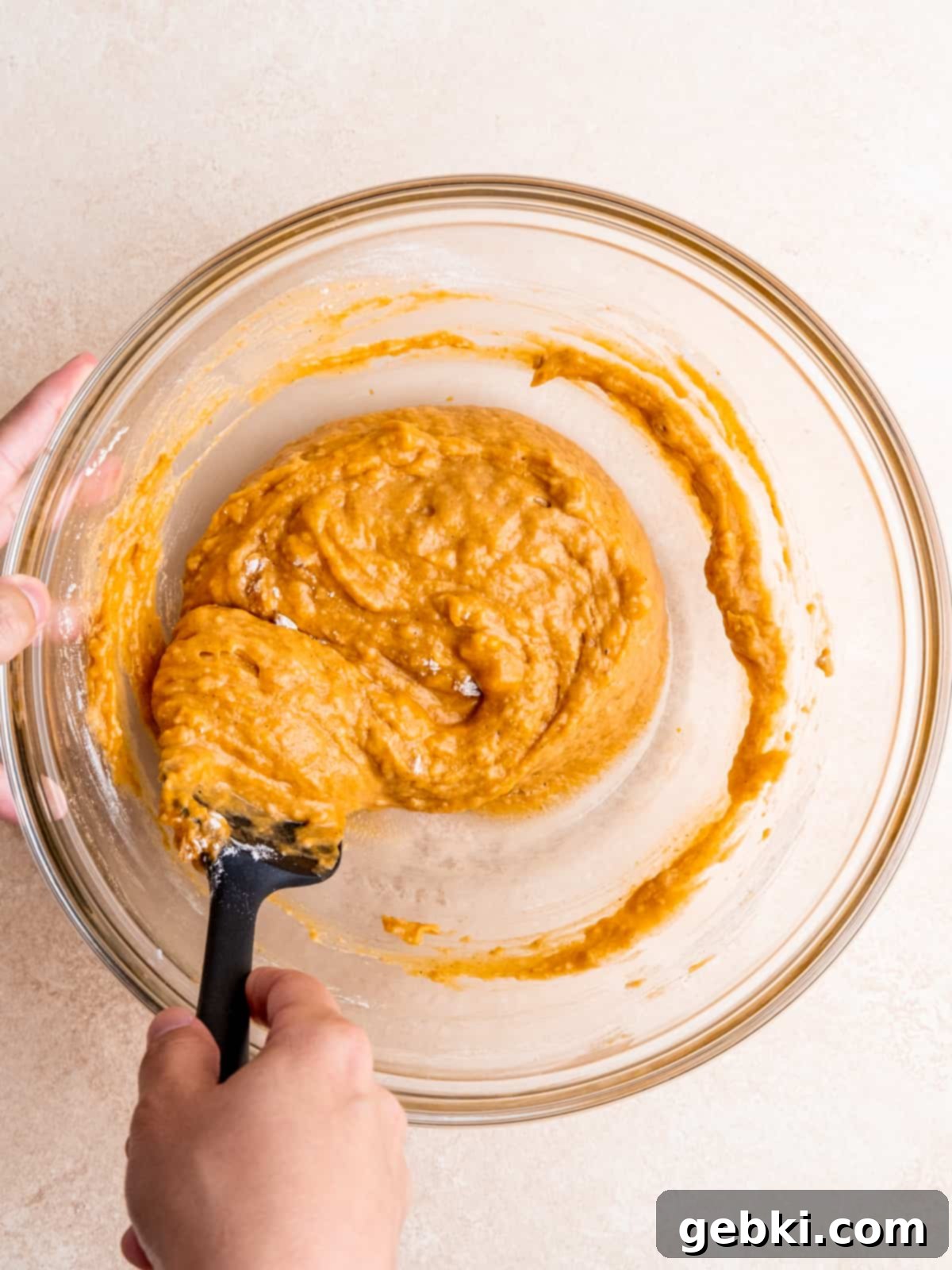 Folding pumpkin muffin batter in a bowl with a spatula, just until combined.