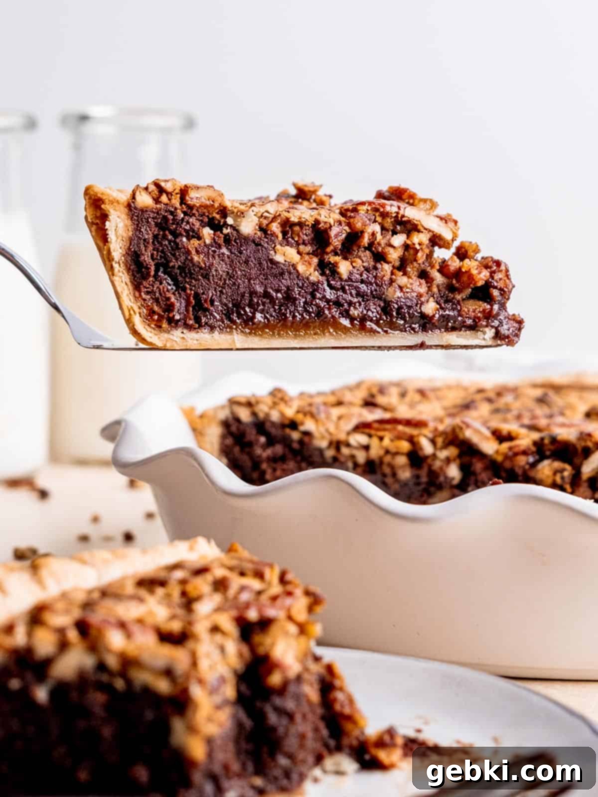 Fudgy Pecan Brownie Pie 2 A slice of pecan brownie pie being lifted out of the pie dish, revealing rich layers.