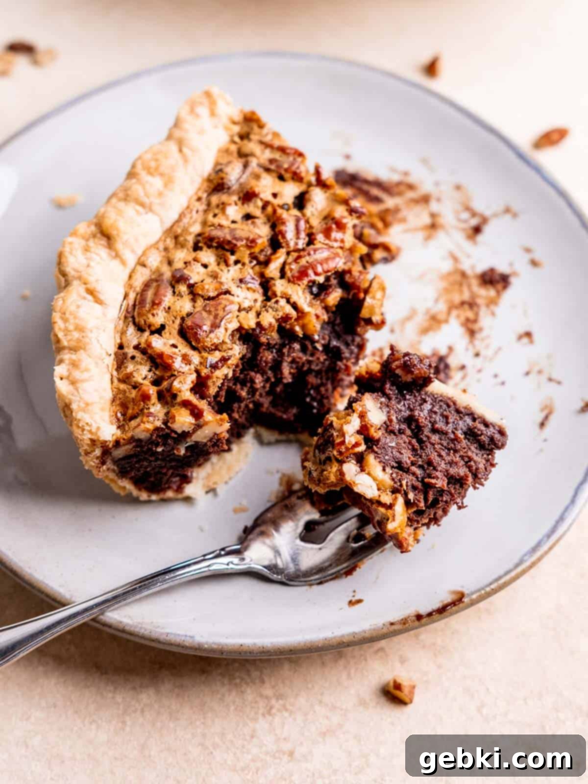 Fudgy Pecan Brownie Pie 10 A perfectly sliced piece of Pecan Brownie Pie on a plate with a fork ready for a bite.